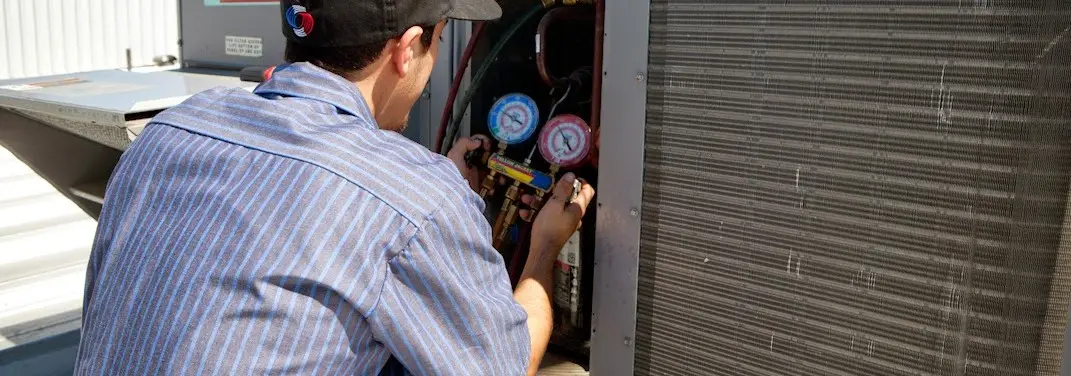 HVAC technician servicing a condenser unit in Lafayette